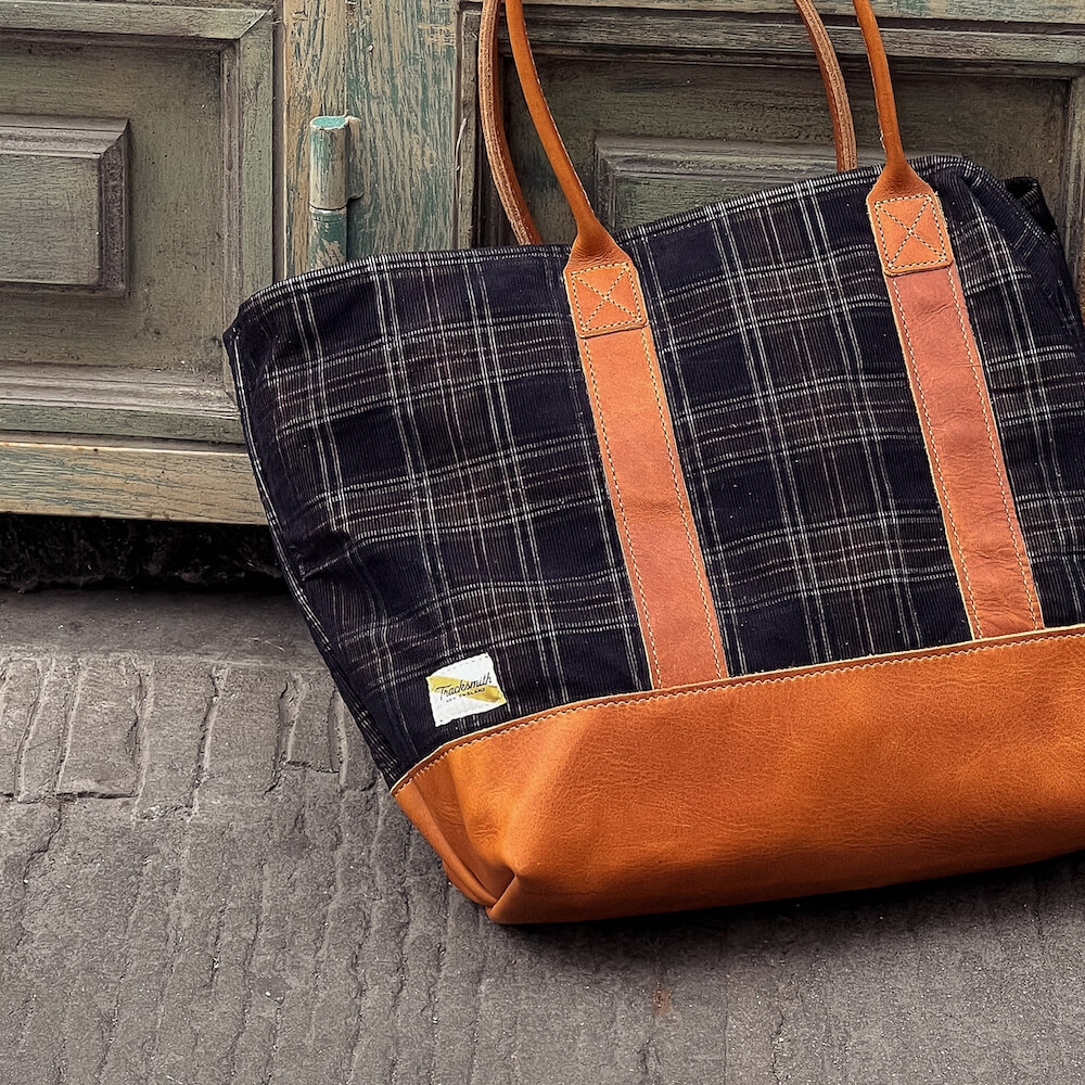 A Tracksmith bag leaning against a wooden door