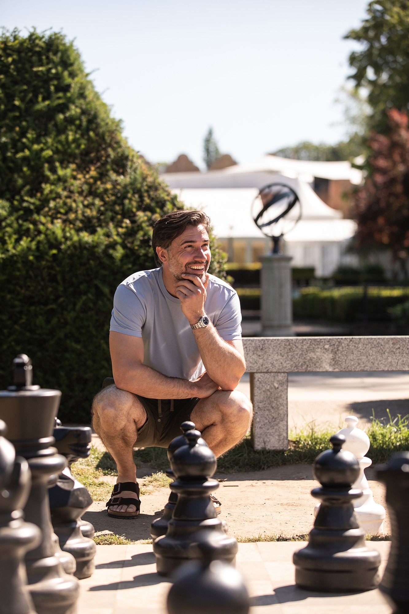 Man crouching next to outdoor chess set