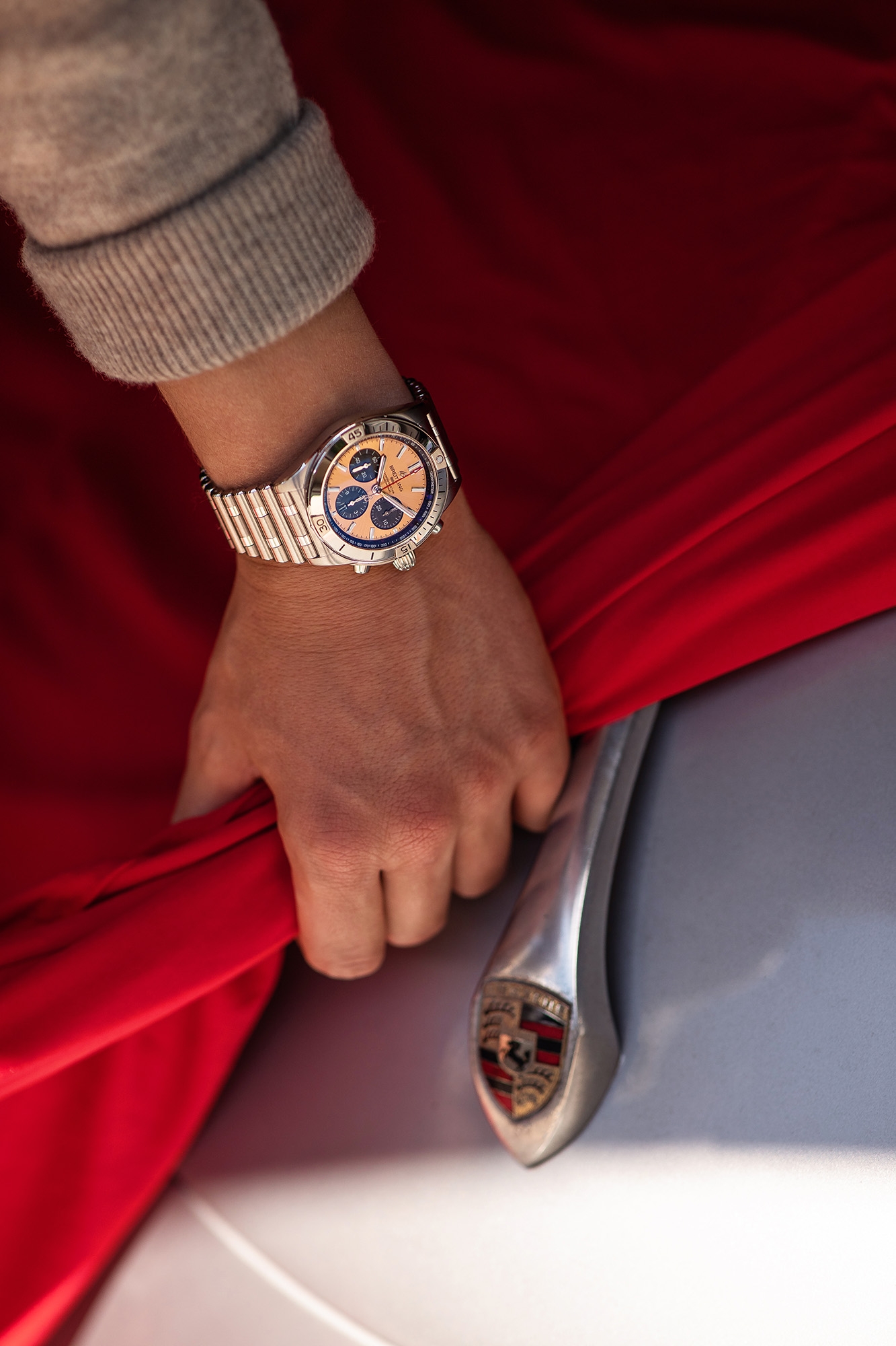 Man wearing Breitling watch covering Porsche with red cloth