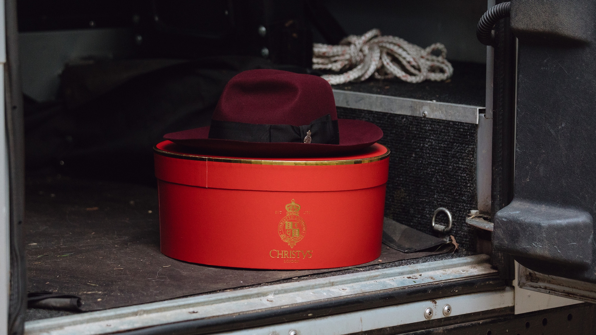 A red Christys’ hat on a hatbox in the back of a Land Rover