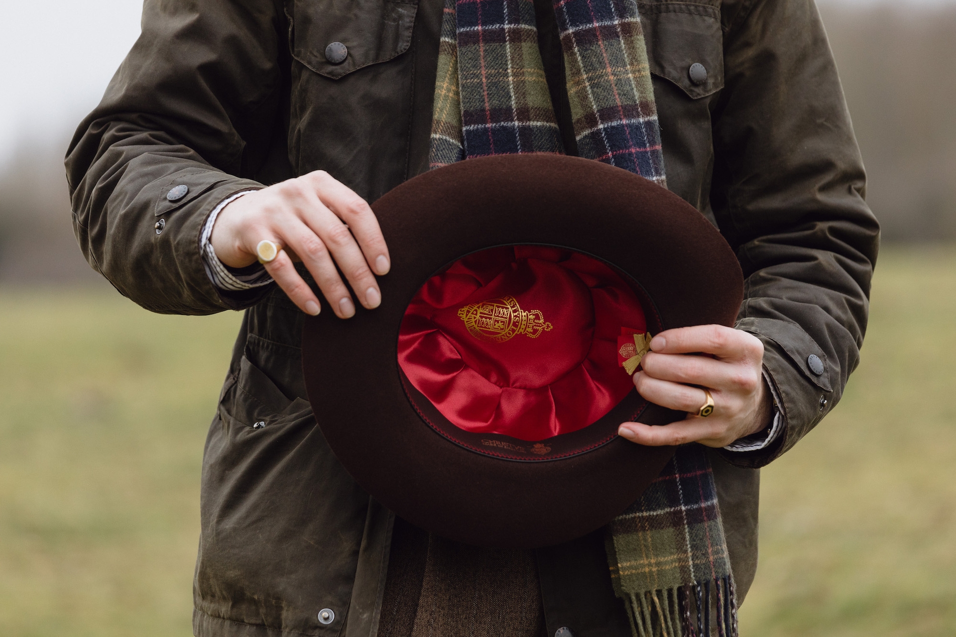 A man in a field showing the red interior of a brown Christys’ hat
