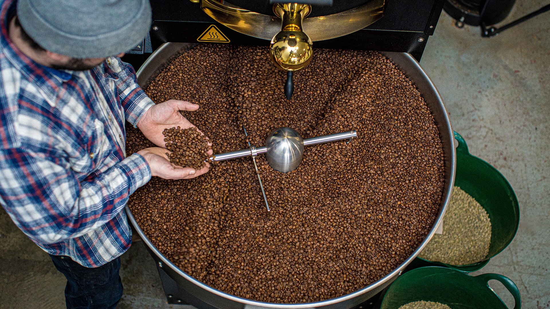 A man holding coffee beans at The Gentlemen Baristas’ Roastery