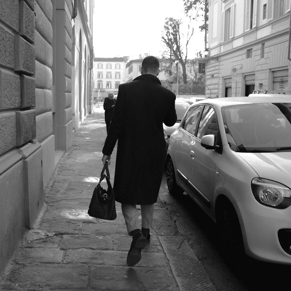 A man holding a bag walking down a street in Florence